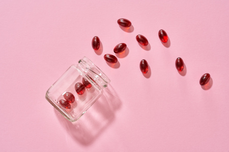umgefallenes Glas mit roten Kapseln