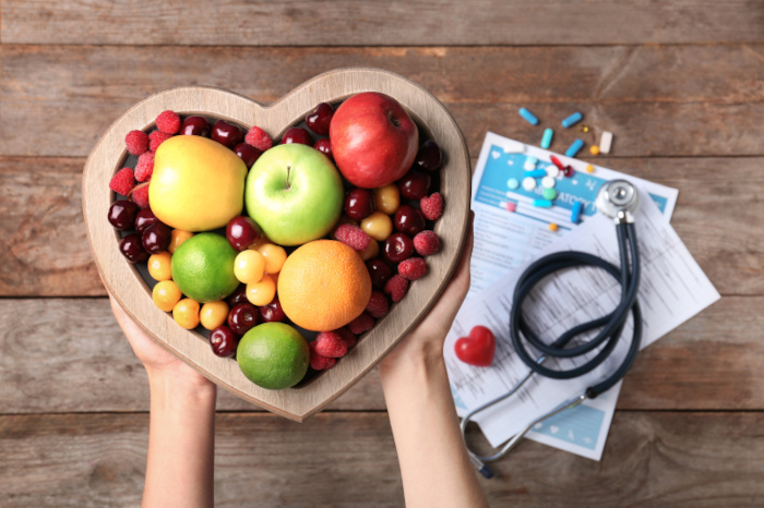 Herzförmige Schale mit Obst, Stethoskop und Medikamente 