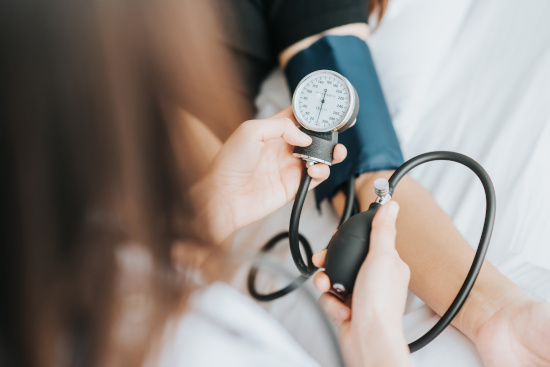 Arzt misst Blutdruck bei Patient